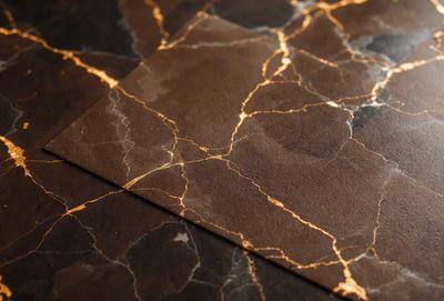 The primary subject of the image is a piece of leather, possibly a wallet or a leather-like material, with a marbled pattern. The setting is a table, and the visual style appears to be a close-up of the leather material. The colors and mood of the image are predominantly brown and black, giving it a sophisticated and elegant appearance.