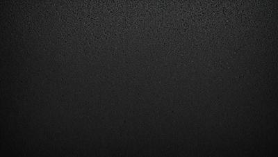The primary subject of the image is a black background with a texture that resembles a black and white photo. The setting is a dark room, and the visual style is a close-up of the black background. The colors and mood of the image are predominantly dark and moody, with a sense of depth and contrast.