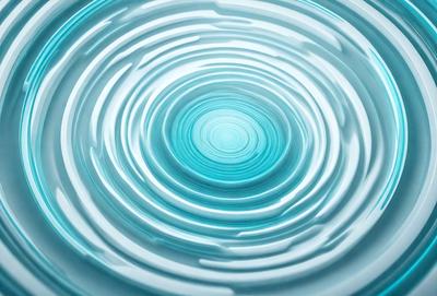 The primary subject of the image is a blue, swirling, circular pattern. The setting is a clear, blue glass surface, which adds to the visual style. The image appears to be a digital art or illustration, with a vibrant and dynamic atmosphere.