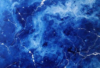The primary subject of the image is a blue marble wall with a pattern of swirls and lines. The setting is a room with a blue marble wall, and the visual style is a close-up of the wall. The dominant colors are blue and white, creating a calm and serene atmosphere.