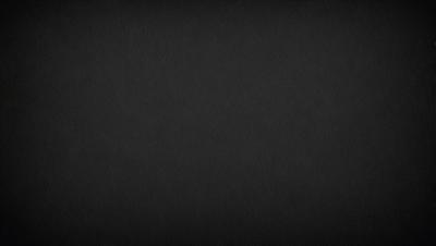 The image is a black and white photo of a dark background. The primary subject is a large, empty space with no visible objects or details. The setting is a black background, which creates a stark contrast with the subject. The visual style is a black and white photo, giving the image a classic and timeless appearance. The colors and mood are predominantly dark and moody, with the black background emphasizing the emptiness of the space.