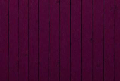 The primary subject of the image is a wooden wall with a purple color. The setting is a room with a wooden surface, and the visual style is a close-up of the wooden wall. The dominant colors are purple and brown, creating a warm and cozy atmosphere.