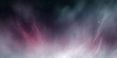 The primary subject of the image is a cloudy sky with a purple hue. The setting is a dark, cloudy night, and the visual style is a photo. The colors and mood of the image are predominantly purple, creating a moody and atmospheric scene.