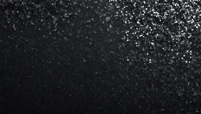 The primary subject of the image is a black background with a pattern of glittering stars. The setting is a dark, starry night, and the visual style is a combination of a photo and digital art. The colors and mood of the image are predominantly dark and mysterious, with the glittering stars adding a touch of brightness and intrigue.