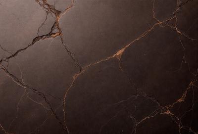 The primary subject of the image is a close-up of a marble countertop with a cracked and peeling surface. The setting is a kitchen, and the visual style is a photo. The dominant colors are brown and black, giving the countertop a worn and aged appearance. The overall atmosphere is one of wear and tear, possibly indicating a need for repair or replacement.