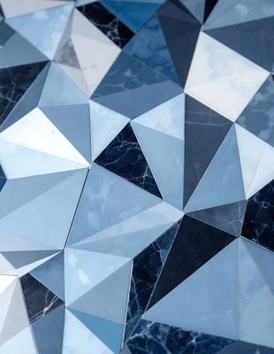 The primary subject of the image is a blue and white marble tile. The setting is a blue and white marble tile wall. The visual style is a close-up of the tile, showcasing its intricate design. The colors and mood of the image are predominantly blue and white, creating a clean and elegant atmosphere.