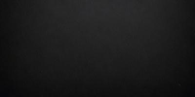 The primary subject of the image is a black leather surface. The setting is a dark room, and the visual style is a close-up of the leather surface. The colors and mood of the image are predominantly dark and moody, with the black leather surface being the main focus.