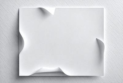 The primary subject of the image is a piece of paper with a creased or folded design. The paper is white and appears to be a piece of cardboard. The setting is a table, and the visual style is a close-up of the paper. The colors and mood of the image are predominantly white, giving it a clean and minimalist appearance.