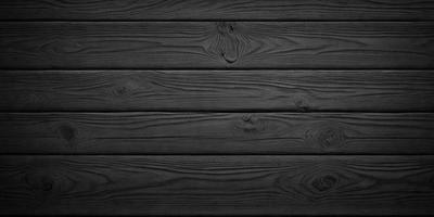 The primary subject of the image is a wooden wall with a black background. The setting is a room with a wooden floor. The visual style is a black and white photo. The dominant colors are black and white, creating a moody atmosphere.