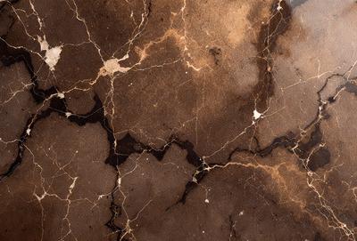 The primary subject of the image is a marble surface with a pattern of holes and lines. The setting is a room with a brown marble wall, which adds to the overall atmosphere. The visual style is a close-up of the marble surface, showcasing its intricate pattern. The colors and mood of the image are predominantly brown, giving it a warm and natural feel.