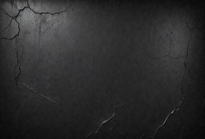 The primary subject of the image is a black wall with a few white spots. The setting is a dark room, and the visual style is a black and white photo. The dominant colors are black and white, creating a moody atmosphere.
