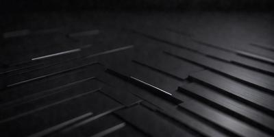 The primary subject of the image is a silver metal piece, possibly a piece of art or a decorative item, placed on a black surface. The setting appears to be a dark room, with the black surface being the main focus of the image. The visual style of the image is a close-up of the silver piece, emphasizing its details and texture. The colors in the image are predominantly black and silver, creating a moody and dramatic atmosphere.