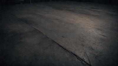 The primary subject of the image is a large, dark grey floor. The setting is a room with a dark, possibly damp, atmosphere. The visual style is a photo, and the colors and mood are predominantly dark and moody.