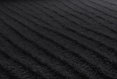 The primary subject of the image is a black and white patterned fabric. The setting is a black background, and the visual style is a close-up of the fabric. The colors and mood of the image are predominantly black and white, giving it a classic and timeless appearance.