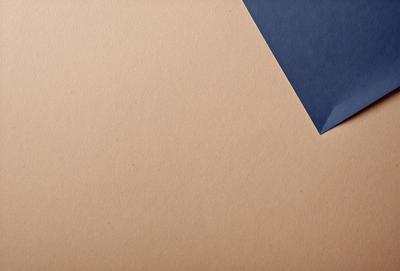 The primary subject of the image is a piece of cardboard with a blue triangle on it. The setting is a table, and the visual style is a photo. The colors and mood of the image are predominantly brown and blue, giving it a simple and minimalistic appearance.