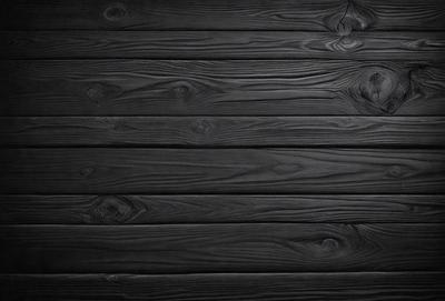 The primary subject of the image is a wooden wall. The setting is a dark room, and the visual style is a black and white photo. The colors and mood of the image are predominantly dark, creating a moody atmosphere.