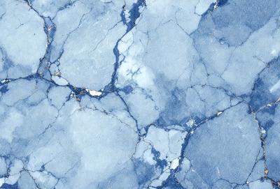 The primary subject of the image is a blue marble surface with a pattern of holes and cracks. The setting is a blue marble wall, and the visual style is a close-up of the marble surface. The dominant colors are blue and white, creating a calm and serene atmosphere.