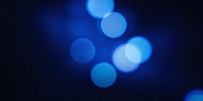 The primary subject of the image is a blue background with a pattern of white lights. The setting appears to be a dark room, and the visual style is a combination of a photo and digital art. The dominant colors are blue and white, creating a calm and serene atmosphere.