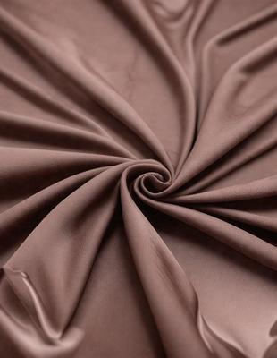 The primary subject of the image is a brown fabric, possibly a piece of cloth or a curtain. The setting is a room with a brown background, and the visual style appears to be a close-up of the fabric. The colors and mood of the image are predominantly brown, giving it a warm and cozy atmosphere.