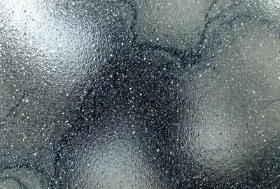 The primary subject of the image is a close-up of a black and white patterned surface, possibly a wall or a piece of art. The setting appears to be a dark room, with the patterned surface being the main focus. The visual style of the image is a combination of a photo and a digital art, creating a unique and intriguing appearance. The colors and mood of the image are predominantly black and white, with a slightly mysterious and artistic atmosphere.