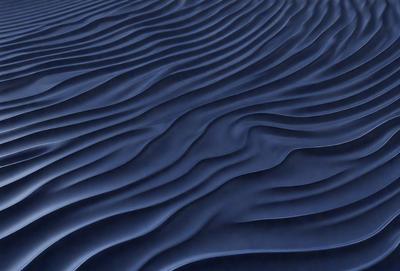 The primary subject of the image is a blue ocean wave. The setting is the ocean, with the wave rolling in. The visual style is a photo of the ocean, capturing the beauty of the wave. The dominant colors are blue and white, creating a serene and calming atmosphere.