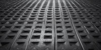 The primary subject of the image is a pattern of hexagonal tiles, which are arranged in a checkered pattern. The setting is a black and white photograph, giving the image a classic and timeless appearance. The visual style is a close-up of the tiles, emphasizing the intricate details of the pattern. The colors and mood of the image are predominantly black and white, creating a sense of depth and contrast.