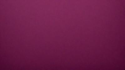 The primary subject of the image is a large, purple wall. The setting is a room with a pink background. The visual style is a close-up of the wall, which gives a sense of depth and texture. The dominant colors are purple and pink, creating a warm and inviting atmosphere.
