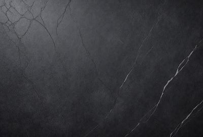 The primary subject of the image is a black marble countertop. The setting is a dark room, and the visual style is a close-up of the marble countertop. The countertop appears to be a dark grey color, giving it a sophisticated and elegant appearance.
