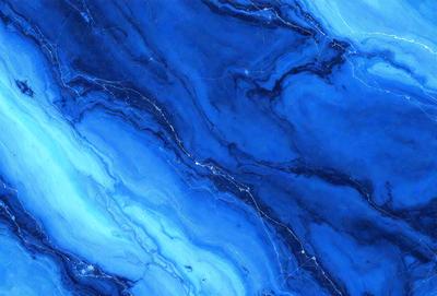 The primary subject of the image is a blue marble tile with a swirling pattern. The setting is a wall, and the visual style is a close-up of the tile. The dominant colors are blue and white, creating a calm and soothing atmosphere.