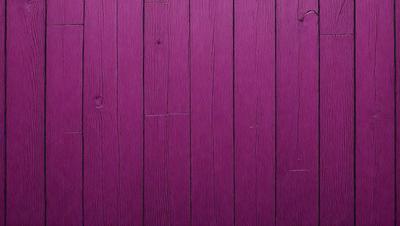 The primary subject of the image is a wooden wall with a purple color. The setting is a room with a wooden floor. The visual style is a close-up of the wooden wall, showcasing its texture and color. The dominant colors are purple and brown, creating a warm and inviting atmosphere.
