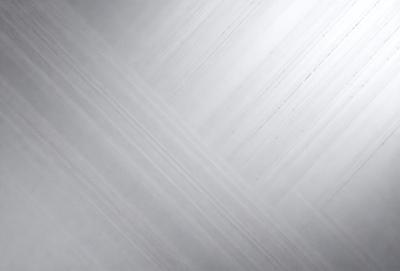 The image features a silver surface with a pattern of lines and curves. The setting appears to be a room with a wall that has a metallic texture. The visual style of the image is a combination of a photo and a digital art, creating a unique and intriguing appearance. The dominant colors in the image are silver and gray, giving the scene a sleek and modern feel.