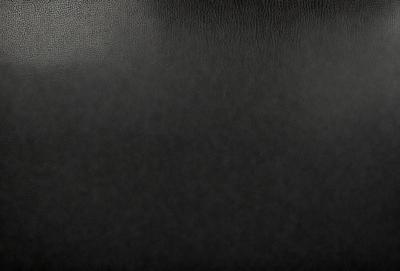 The primary subject of the image is a black leather seat. The setting is a dark room, and the visual style is a close-up of the seat. The colors and mood of the image are predominantly dark, with the black leather seat being the main focus.