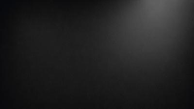 The primary subject of the image is a black background with a white light source. The setting is a dark room, and the visual style is a black and white photo. The colors and mood of the image are predominantly dark and moody, with the white light source providing a contrasting element.