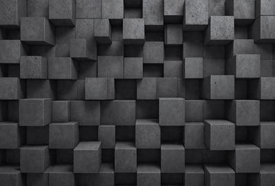 The primary subject of the image is a large, gray brick wall. The setting is a dark room, and the visual style is a black and white photo. The dominant colors are gray and black, creating a moody atmosphere.