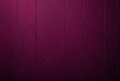 The primary subject of the image is a wooden wall with a purple color. The setting is a room with a wooden surface, and the visual style appears to be a photo. The dominant colors are purple and brown, creating a warm and cozy atmosphere.