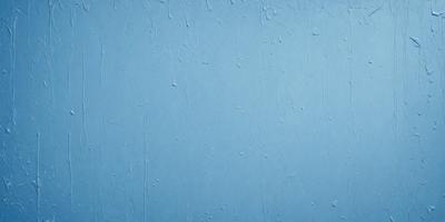 The primary subject of the image is a blue wall with a wet, shiny surface. The setting is a room with a blue background. The visual style is a close-up of the blue wall, which gives a sense of depth and texture. The colors and mood of the image are predominantly blue, creating a calm and serene atmosphere.