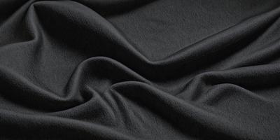 The primary subject of the image is a black fabric, which is the main object, scene, or focus of the image. The setting or background is a black surface, and the visual style is a photo. The colors and mood of the image are predominantly black, creating a dark and moody atmosphere.
