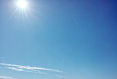 The primary subject of the image is the clear blue sky with a few clouds. The setting is a cloudy day, and the visual style is a photo. The colors and mood of the image are predominantly blue, with a few white clouds, creating a serene and peaceful atmosphere.