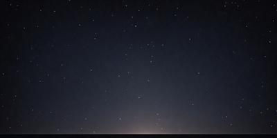 The primary subject of the image is the night sky filled with stars. The setting is a dark, starry night, with the stars scattered across the sky. The visual style is a black and white image, which adds a sense of timelessness and nostalgia to the scene. The colors and mood of the image are predominantly dark and moody, with the stars providing a contrasting and serene element to the overall atmosphere.