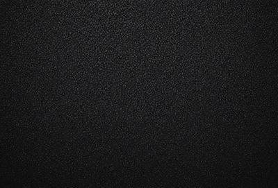 The primary subject of the image is a black leather surface. The setting is a black background, and the visual style is a close-up of the leather surface. The colors and mood of the image are predominantly dark and moody, with the black leather creating a striking contrast against the black background.
