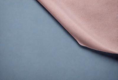 The primary subject of the image is a piece of pink fabric, which is placed on a blue surface. The setting appears to be a room with a table, and the visual style is a close-up of the fabric. The colors in the image are predominantly pink and blue, creating a calm and soothing atmosphere.