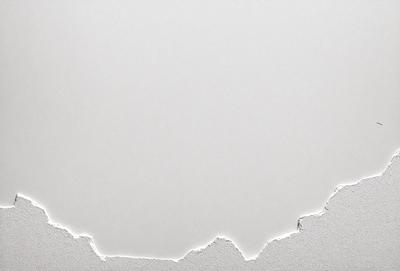 The primary subject of the image is a white wall with a peeling paint surface. The setting is a room with a white background. The visual style is a photo of the wall, showcasing the peeling paint. The colors and mood of the image are predominantly white, giving it a clean and minimalist appearance.