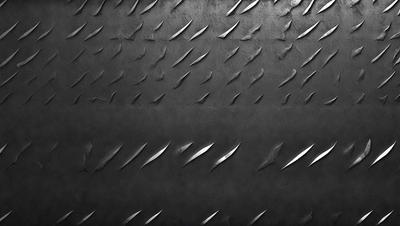 The primary subject of the image is a close-up of a black leather surface with a pattern of metal spikes or blades. The setting is a dark room, and the visual style appears to be a combination of a photo and a digital art or illustration. The dominant colors are black and silver, creating a moody and dramatic atmosphere.
