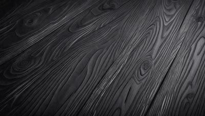 The primary subject of the image is a wooden floor with a unique and intricate pattern. The setting is a room with a black background, which emphasizes the wooden floor's design. The visual style is a close-up of the wooden floor, showcasing its details. The colors and mood of the image are dark and moody, with the wooden floor being the main focus.