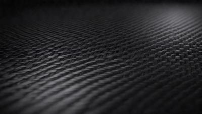 The primary subject of the image is a close-up of a black and white patterned fabric. The setting is a dark background, which contrasts with the patterned fabric. The visual style is a black and white photo, giving the image a classic and timeless appearance. The colors and mood of the image are predominantly dark and moody, with the patterned fabric serving as the focal point.