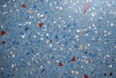 The primary subject of the image is a blue and white mosaic tile wall. The setting is a room with a blue and white tile floor. The visual style is a close-up of the tile wall, showcasing the intricate design and patterns. The dominant colors are blue and white, creating a clean and modern atmosphere.
