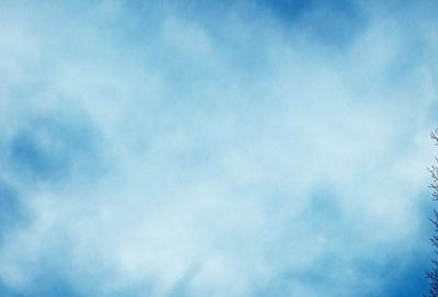 The primary subject of the image is a cloudy blue sky. The setting is a vast, open space with no visible landmarks or objects. The visual style is a natural, outdoor scene. The colors and mood are predominantly blue and calm, with a hint of tranquility.