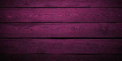 The primary subject of the image is a wooden floor with a purple color. The setting is a room with a wooden wall, and the visual style is a close-up of the wooden floor. The colors and mood of the image are predominantly purple, creating a calm and serene atmosphere.