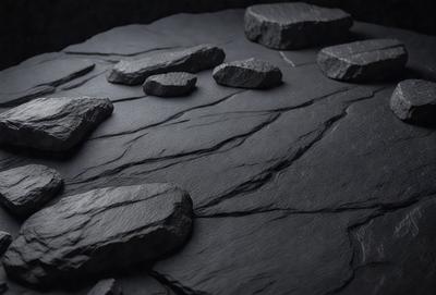 The primary subject of the image is a large rock, which is the main object in the scene. The rock is placed on a black surface, which could be a table or a countertop. The visual style of the image is a photo, capturing the rock in its natural environment. The colors and mood of the image are dark and moody, with the black surface and the rock creating a dramatic and intense atmosphere.