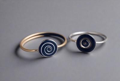 The primary subject of the image is a pair of bracelets, one gold and one silver, with blue and black accents. They are placed on a grey surface, which serves as the setting and background of the image. The visual style of the image is a close-up of the bracelets, showcasing their design and details. The colors and mood of the image are predominantly neutral, with the grey surface and the blue and black accents adding a touch of contrast and interest to the overall composition.